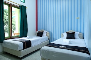 Twee enkele bedden met witte beddengoed en zwarte accenten, een raam met groene gordijnen en een blauwe muur met strepen.