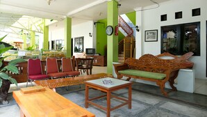 Une pièce spacieuse avec un banc en bois, un canapé et une table à manger. On y trouve un escalier avec une rampe en bois et une horloge au mur.
