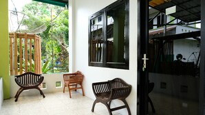 Une pièce avec deux bancs en bois, une porte en verre et une vue sur la verdure à l’extérieur.
