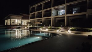 A nighttime swimming pool area with a building in the background. - Aranya Resort Koh Lanta (Ko Lanta)