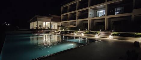 Una piscina al aire libre, sombrillas, sillones reclinables de piscina