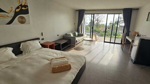 A hotel room with a large bed, a sofa, a small table, a TV, and a balcony with a view. - Aranya Resort Koh Lanta (Ko Lanta)