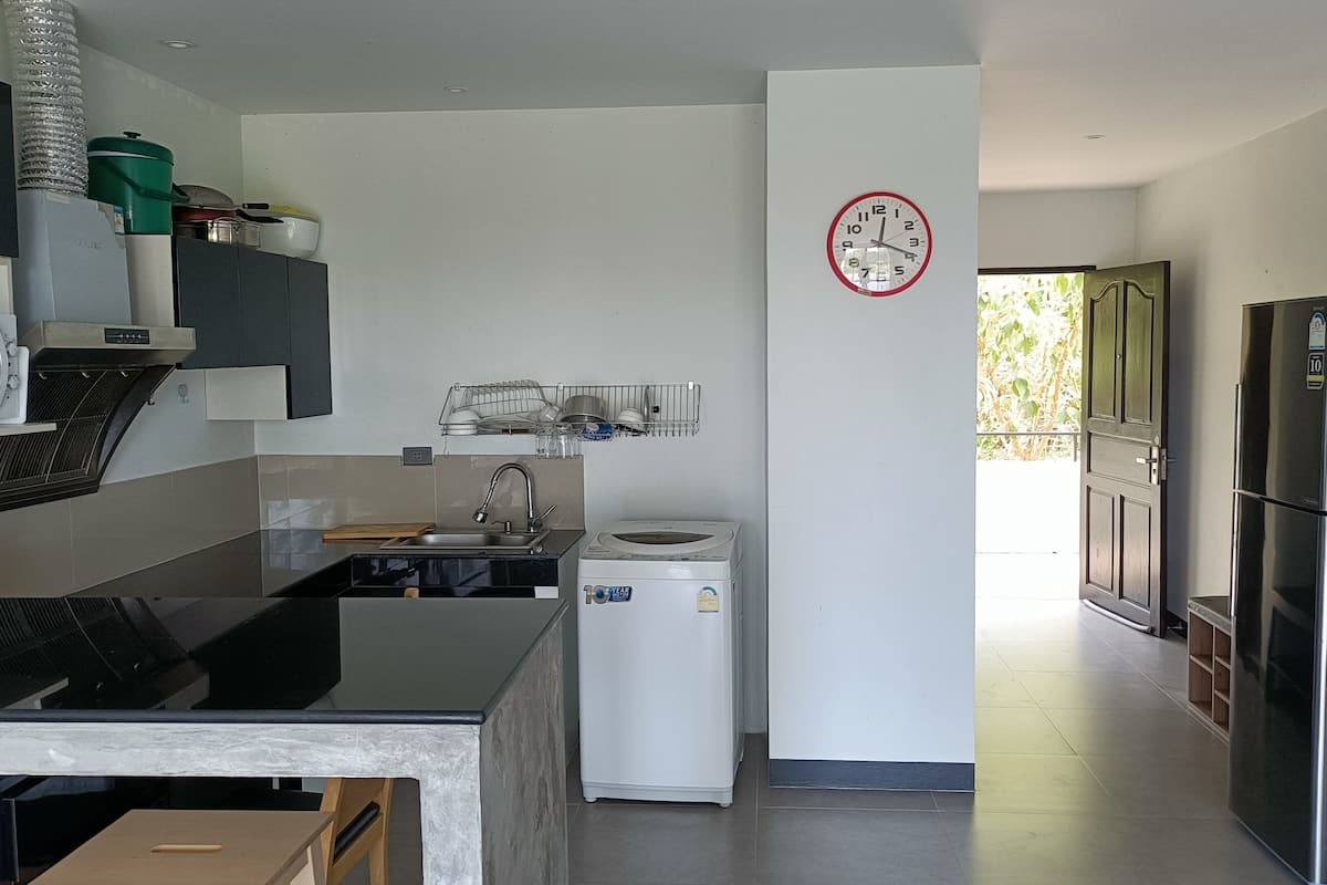 A modern kitchen with a built-in oven, a sink, a dish rack, and a refrigerator.