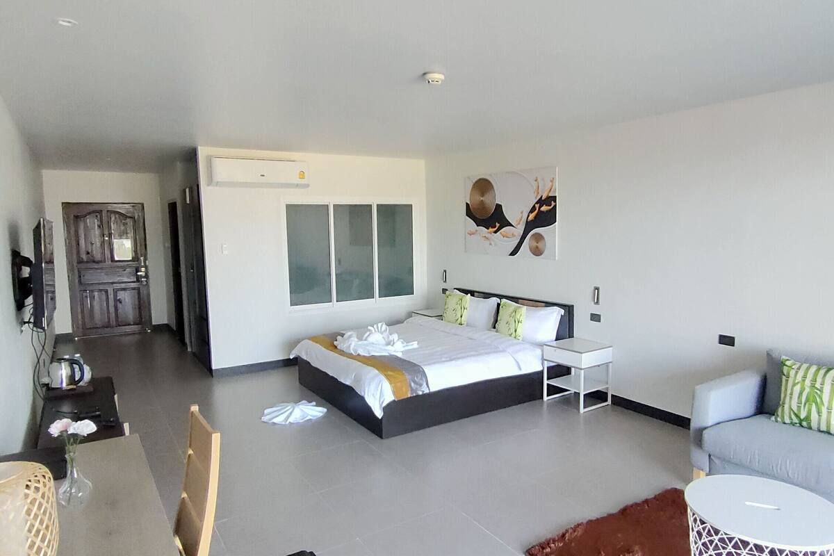 A modern hotel room with a large bed, a sofa, a small table, and a TV.