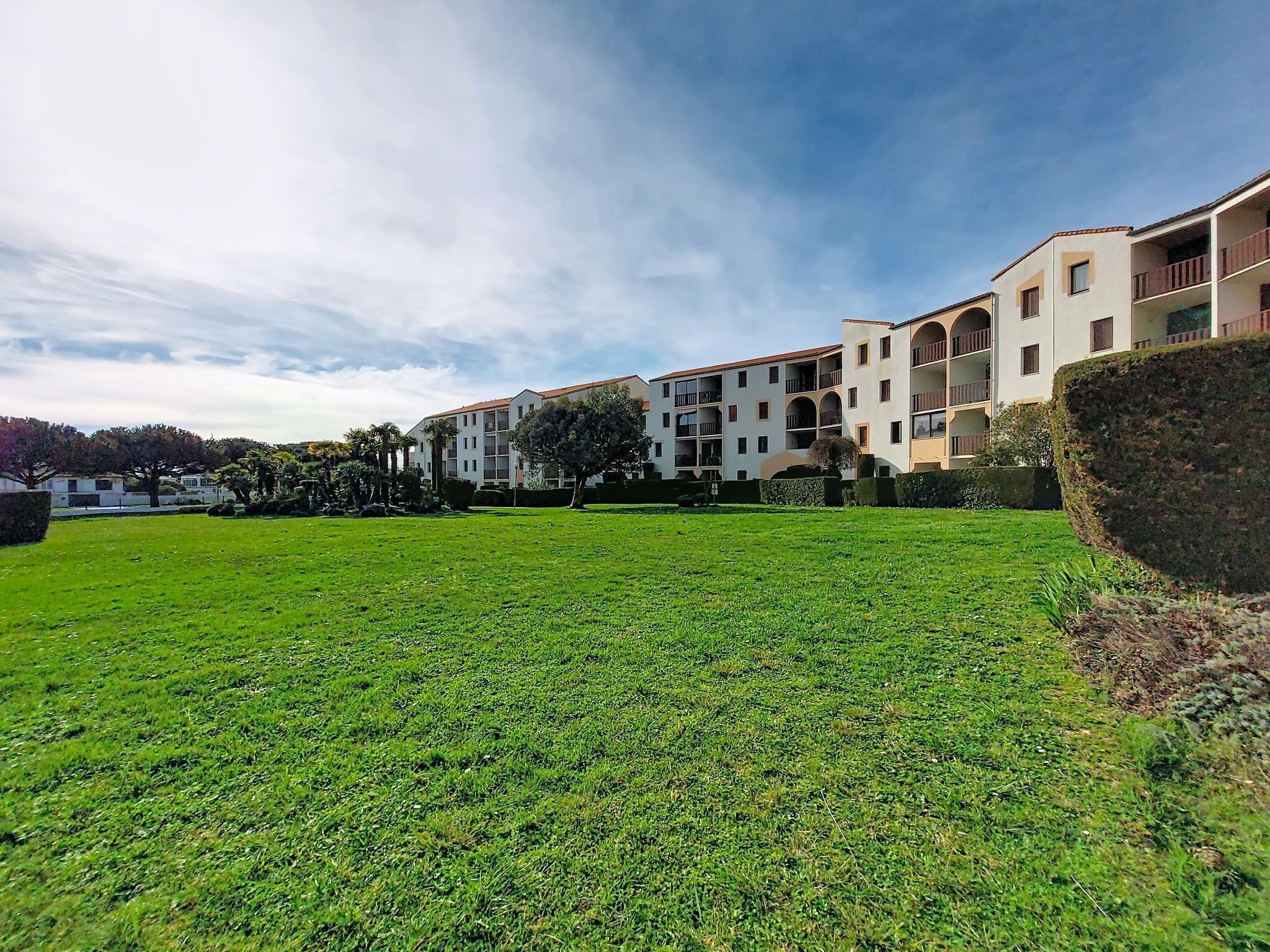 Un edificio residencial con varios balcones y un césped cuidado.