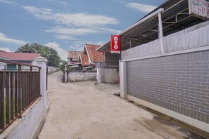 A narrow alleyway with a gated entrance, a covered area with a sign, and buildings with red-tiled roofs. - Super OYO 1868 Penginapan Sekip (Palembang)
