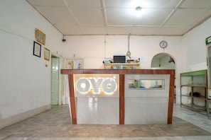 A reception desk with a sign that reads "OYO" and a clock on the wall. - Super OYO 1868 Penginapan Sekip (Palembang)