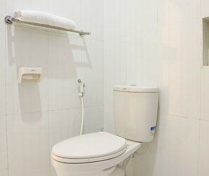A white toilet with a tank, a towel rack, and a paper towel dispenser. - Super OYO 1868 Penginapan Sekip (Palembang)