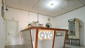 Een receptiebalie met een 'OYO' bord, een klok aan de muur en een Minumat koelkast.