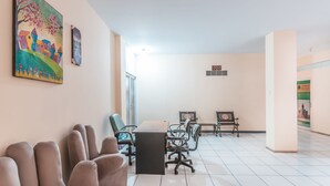 A spacious conference room with a long table, several chairs, and a bench. - Hotel O J&b Room Pramuka (Jakarta)