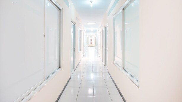 A long, narrow hallway with white walls and large windows on both sides. - Hotel O J&b Room Pramuka (Jakarta)
