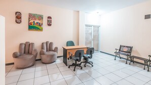 A room with a desk, two office chairs, a bench, and a painting on the wall. - Hotel O J&b Room Pramuka (Jakarta)
