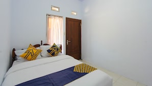 A bedroom with a bed, a wooden door, and a window with curtains. - SPOT ON 2022 Darman Family Residence Syariah (Banyuwangi)