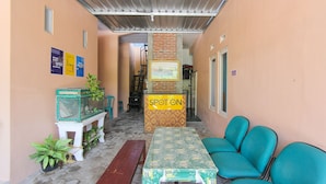A covered outdoor seating area with a table and chairs, a bench, and a sign labeled "SPOTON". - SPOT ON 2022 Darman Family Residence Syariah (Banyuwangi)