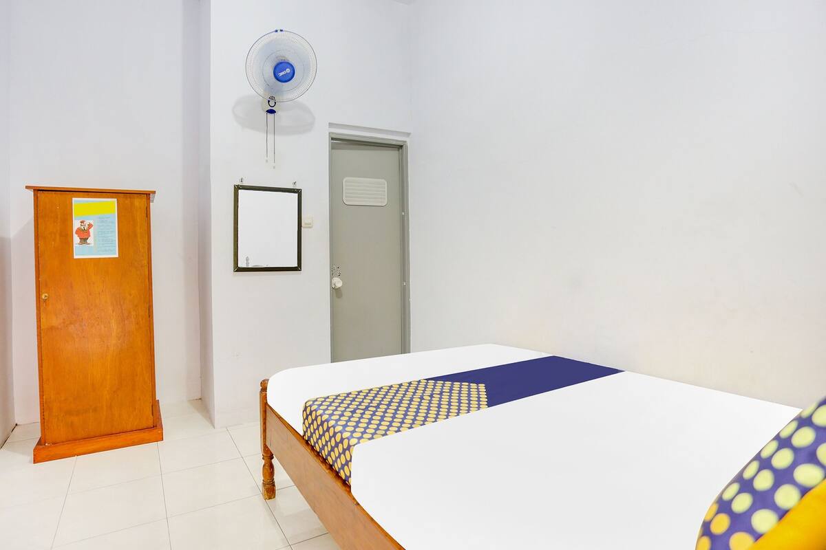 Una habitación con una cama, un armario de madera, una pizarra y una puerta.