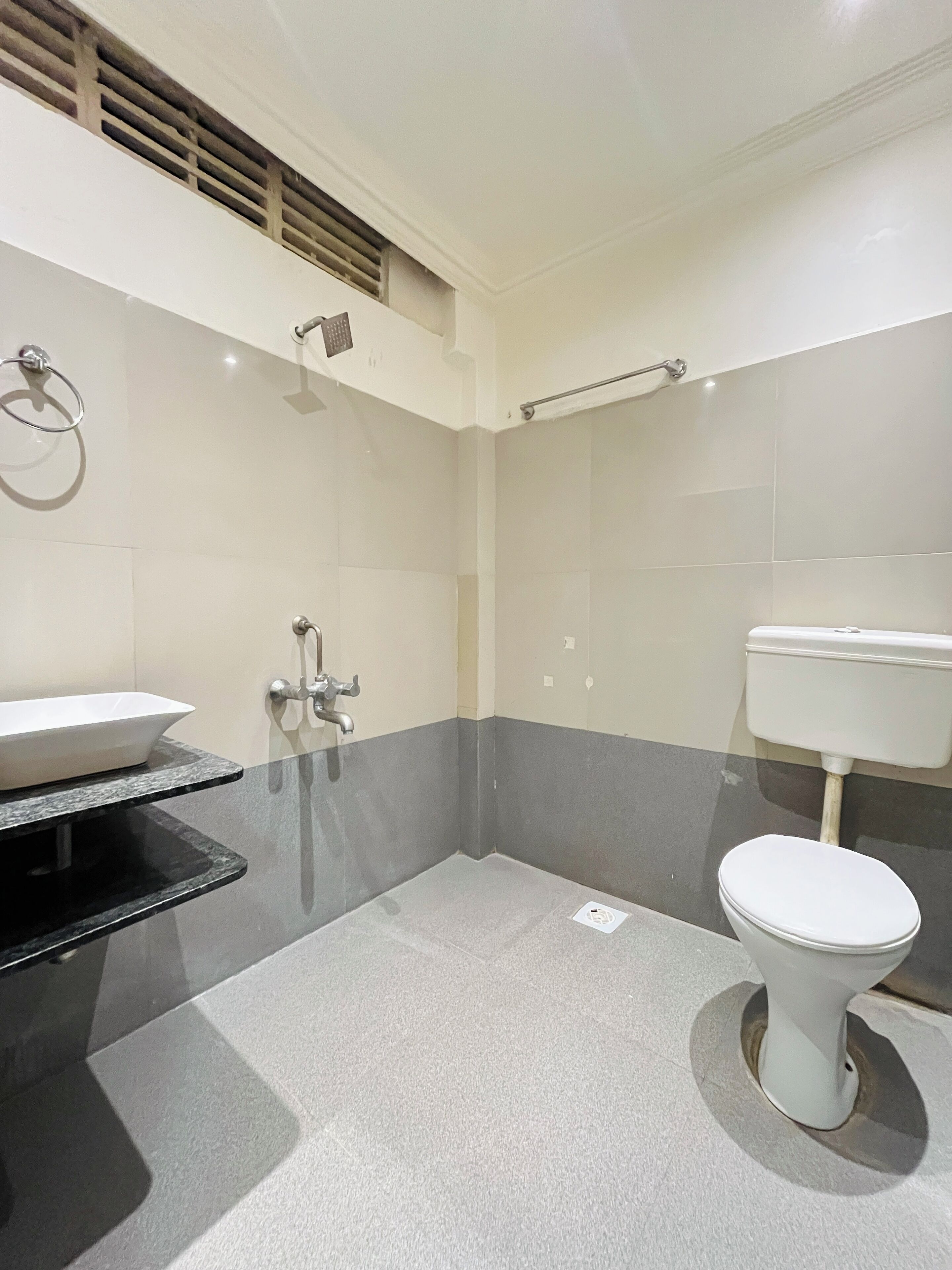 Ein Badezimmer mit einer weißen Toilette, einem schwarzen Waschbecken und einer Dusche.
