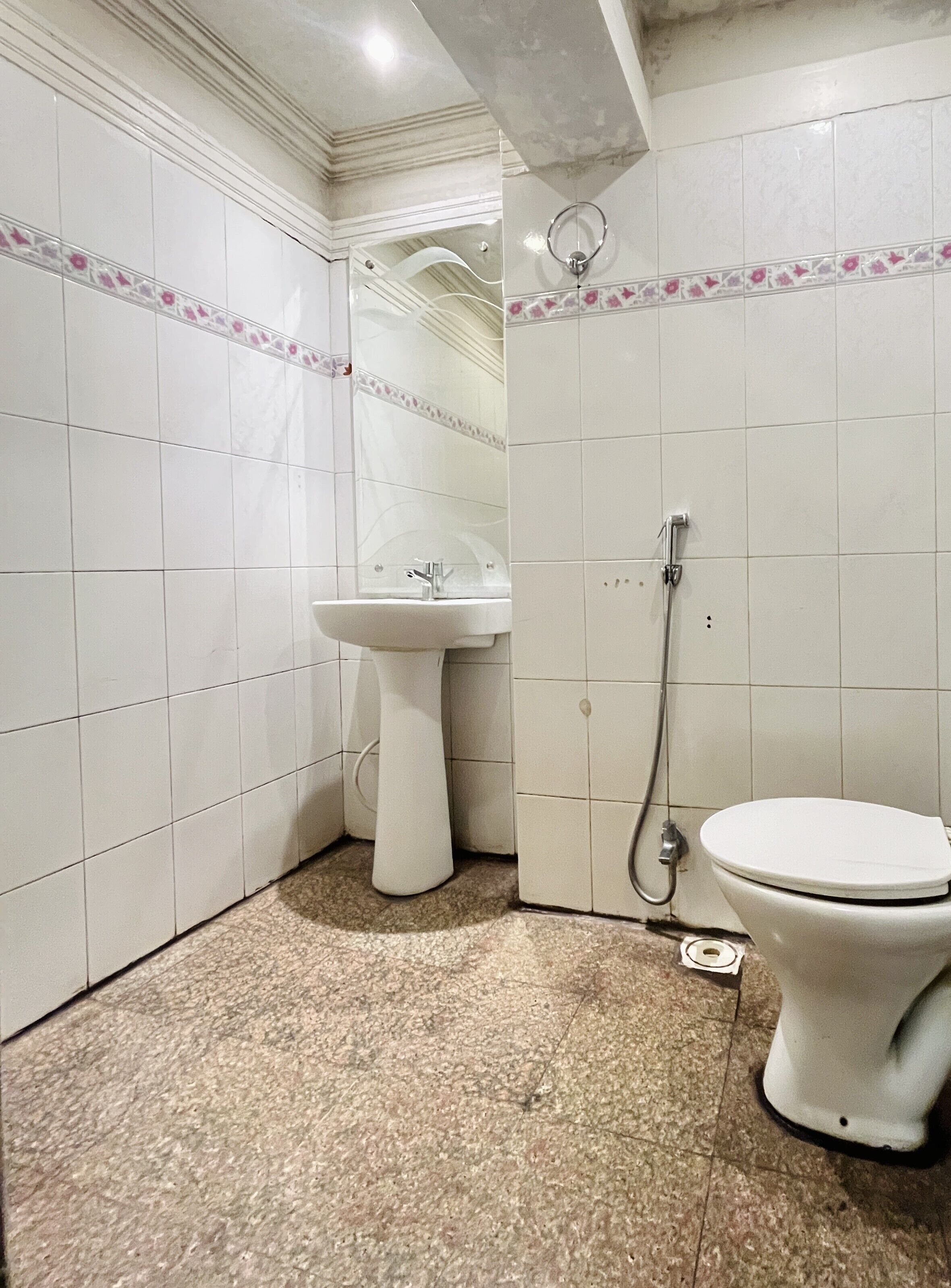 A bathroom with white tiled walls, a sink, a toilet, and a shower.