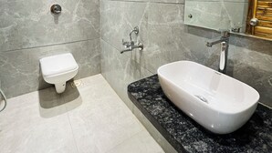 A modern bathroom with a white toilet, a freestanding sink with a marble countertop, and a large mirror. - Hotel Shripad Continental (Amravati)