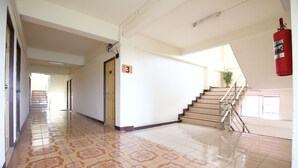 A hallway with patterned tiles, a fire extinguisher, and a staircase. - OYO 689 Baan Yuyuen (Pathum Thani)
