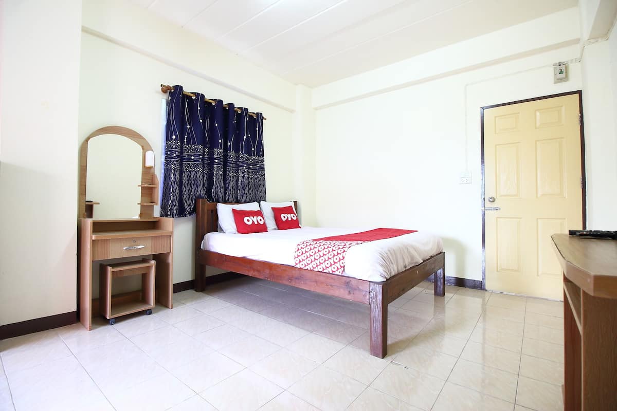 Un dormitorio con cama de madera, un escritorio pequeño de madera, un espejo y una puerta.