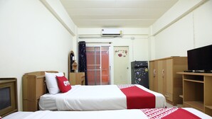 A hotel room with two beds, a television, a wardrobe, and a door leading to a balcony. - OYO 689 Baan Yuyuen (Pathum Thani)