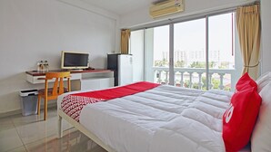 Ein Hotelzimmer mit einem Bett, einem Schreibtisch mit Computer, einem Fernseher und einem Fenster mit Vorhängen.