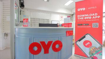 A reception desk with a large OYO logo, a Samsung device, and a red promotional poster for the OYO app.