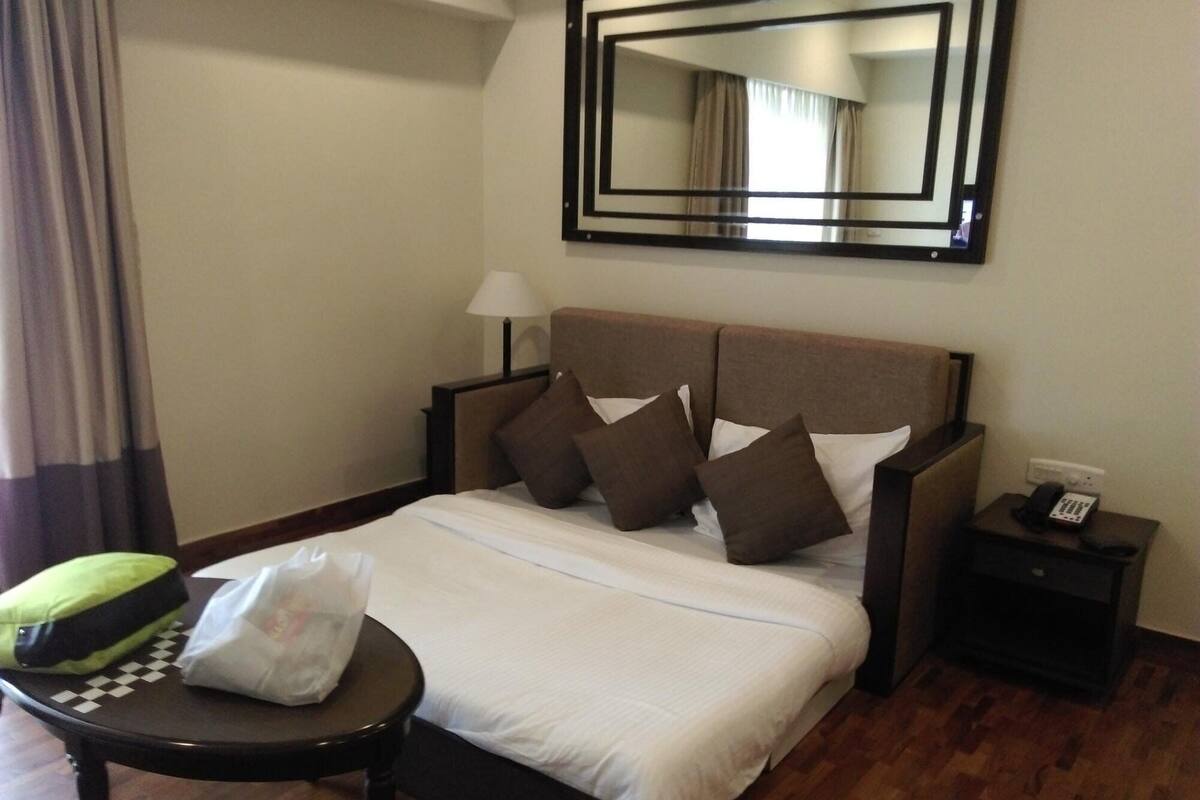 A hotel room with a bed, a nightstand, a lamp, a chair, and a mirror.