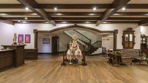 A spacious lobby with a grand staircase, wooden furniture, and a statue. - Club Mahindra Mount Serene Resort in Munnar (Devikolam)