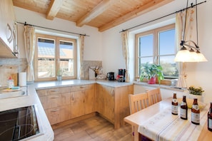 Une cuisine avec des meubles de rangement en bois, une table à manger ornée de bouteilles et une fenêtre avec des rideaux.