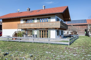Un bâtiment à deux étages doté d’un balcon, de panneaux solaires et d’une cour clôturée.