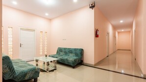 Un hall d’hôtel avec un comptoir d’accueil, un canapé et un divan à motifs.