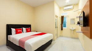 Une chambre d’hôtel comprenant un lit, une table de chevet, une télévision, une fenêtre et une salle de bain avec un lavabo et un miroir.