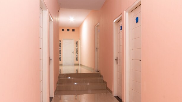 Un couloir doté d’un sol en marbre, de portes blanches et d’un mur orné de motifs.
