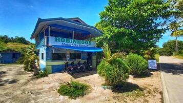A building with a sign reading "ROBINHOOD Motorbike Rental" and several motorcycles parked outside.