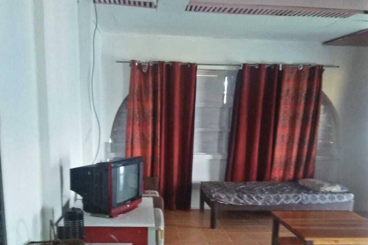 A living room with a television, a sofa, a small table, and a blue cabinet.