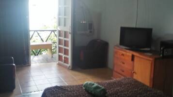 A bedroom with a bed, a television, a dresser, and a suitcase.