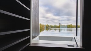 A modern bathroom with a large window, a bathtub, and a towel rack. - Gorgeous Lakeside Villa with wellness SPA and 8 seater cinema (Lechlade-on-Thames)