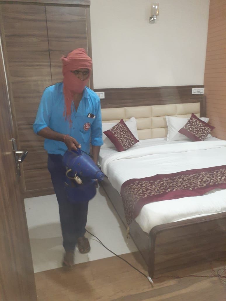 A room with a bed, a wardrobe, and a person holding a blue object.