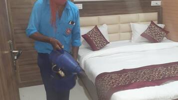 A room with a bed, a wardrobe, and a person holding a blue object.