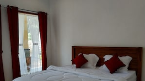 A bedroom with a wooden bed, white bedding, and red pillows. - Omah Nusa Villa (Penida Island)