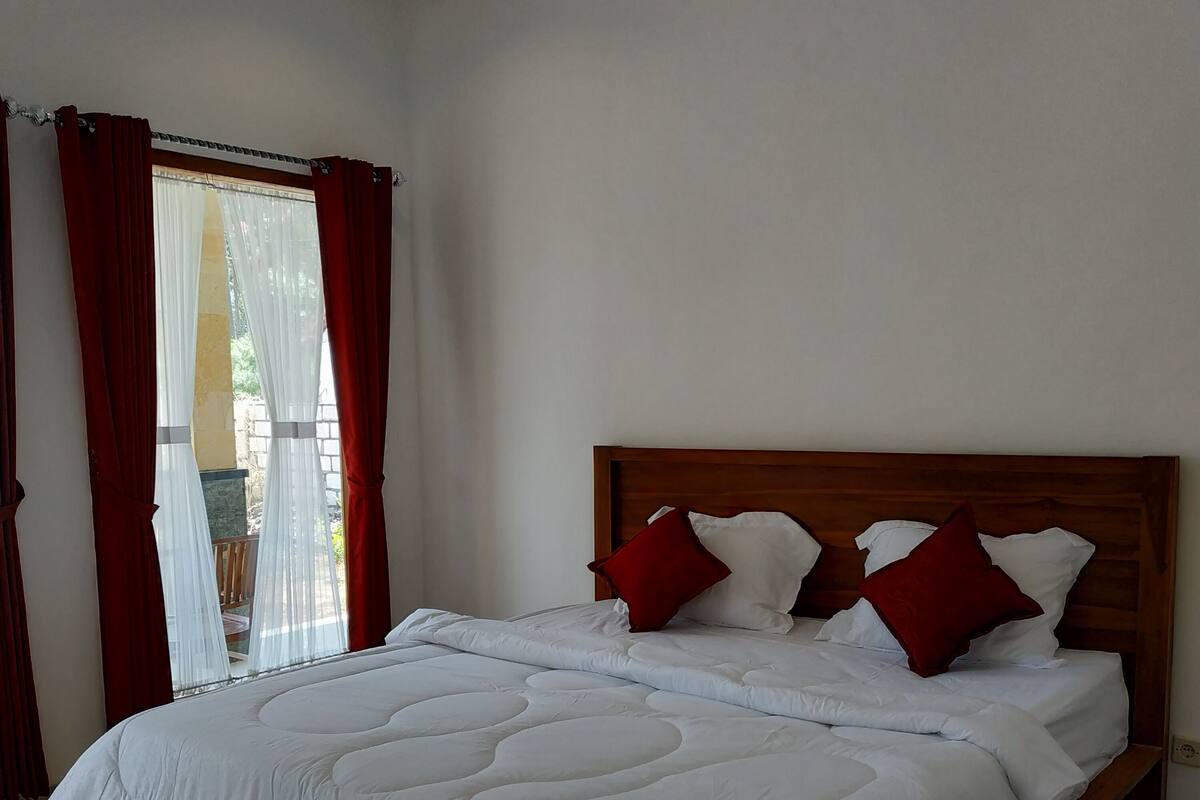 A bedroom with a wooden bed, white bedding, and red pillows.