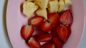 A pink plate with pineapple chunks and sliced strawberries. - Omah Nusa Villa (Penida Island)