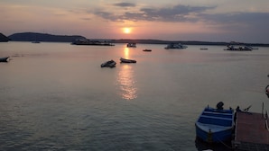 A calm body of water with boats and a distant shoreline during sunset. - Omah Nusa Villa (Penida Island)