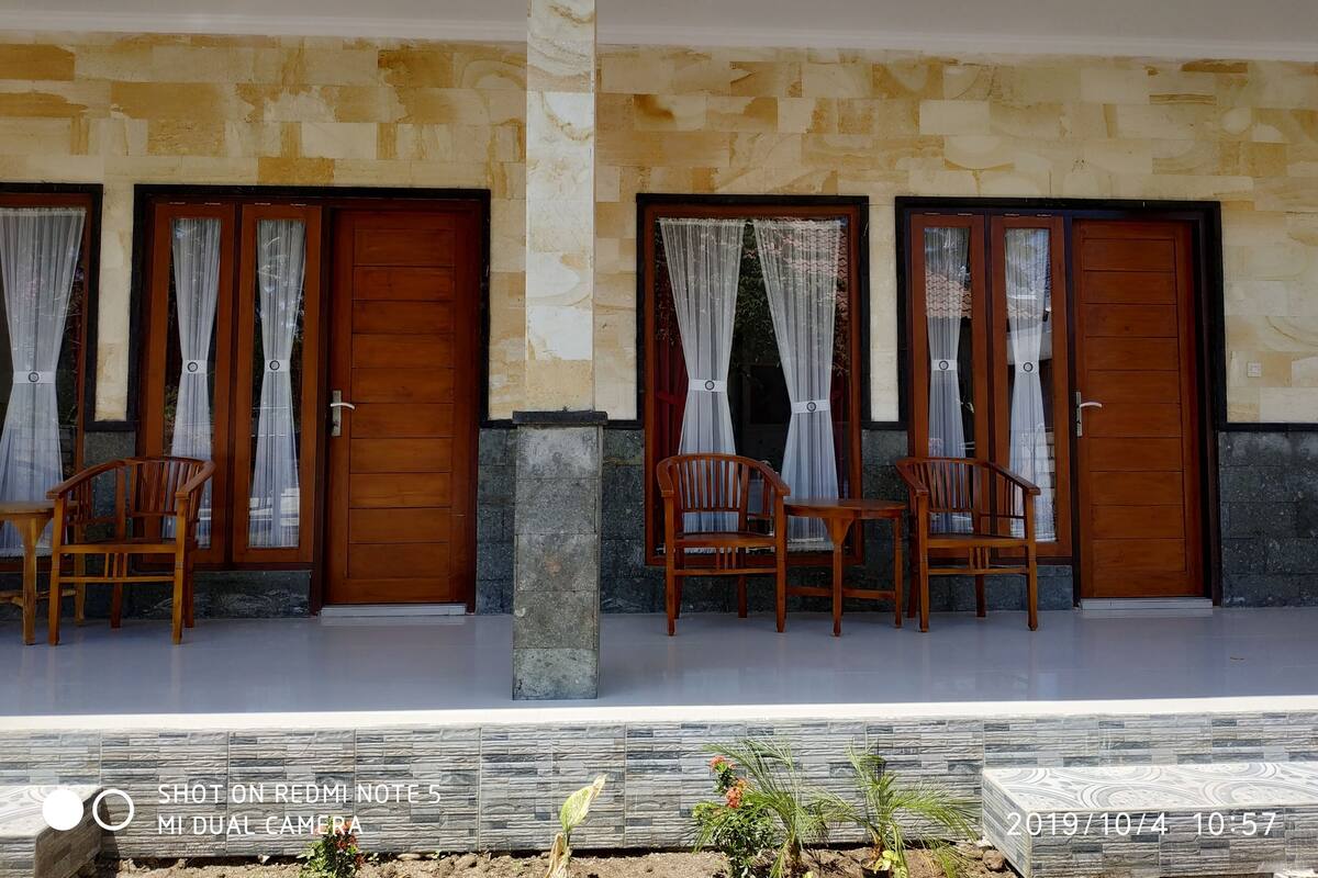 A hotel entrance with two wooden doors, each flanked by a pair of wooden chairs and a table.