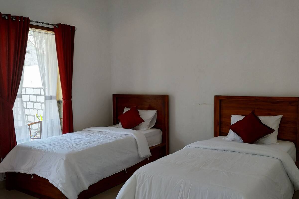 Two single beds with wooden headboards and white bedding in a room with a plain white ceiling and walls.