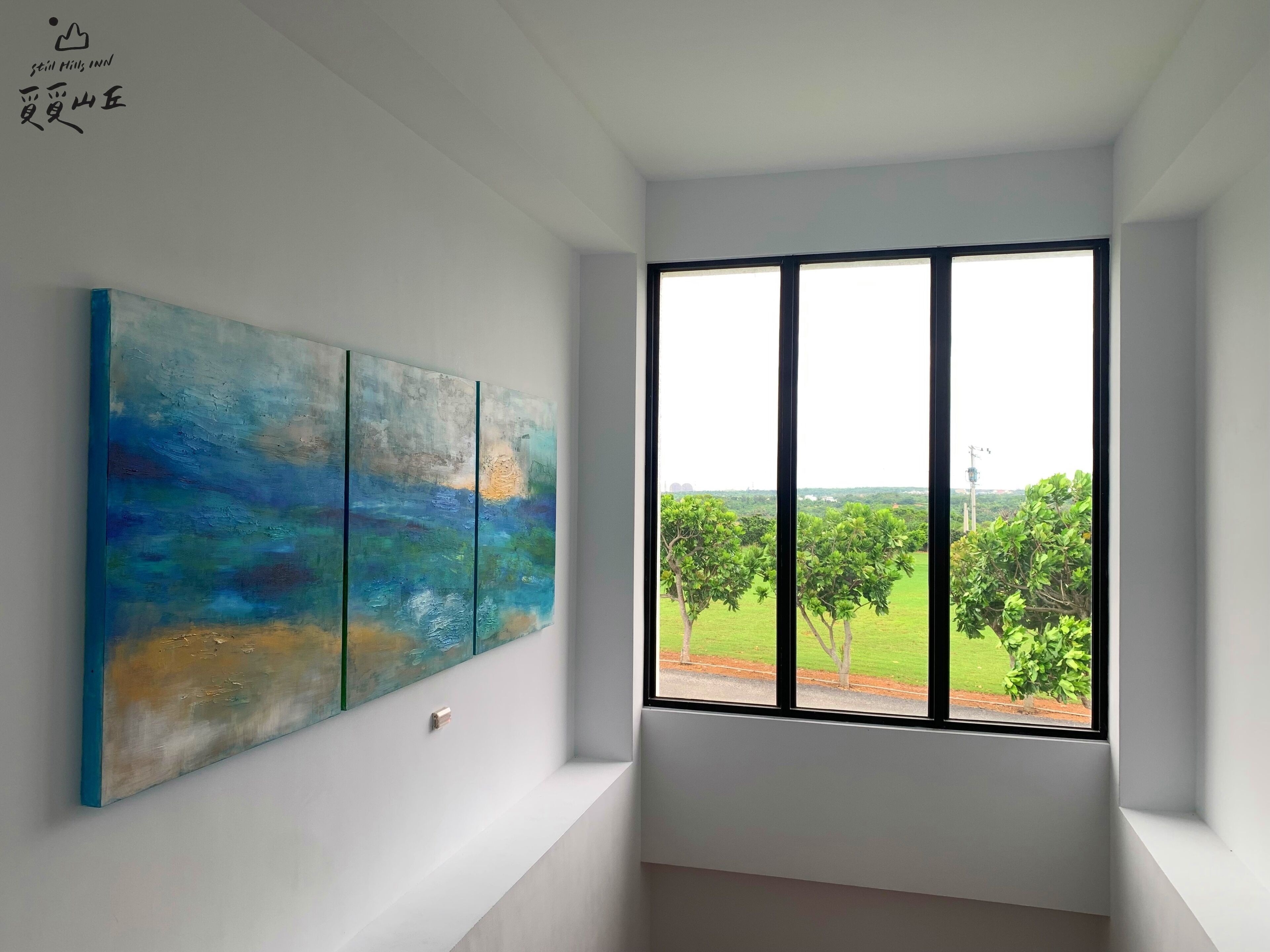 Una habitación con un ventanal grande, un cuadro en la pared y una lámpara en el techo.