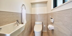 A modern bathroom with a bathtub, toilet, and hand dryer.