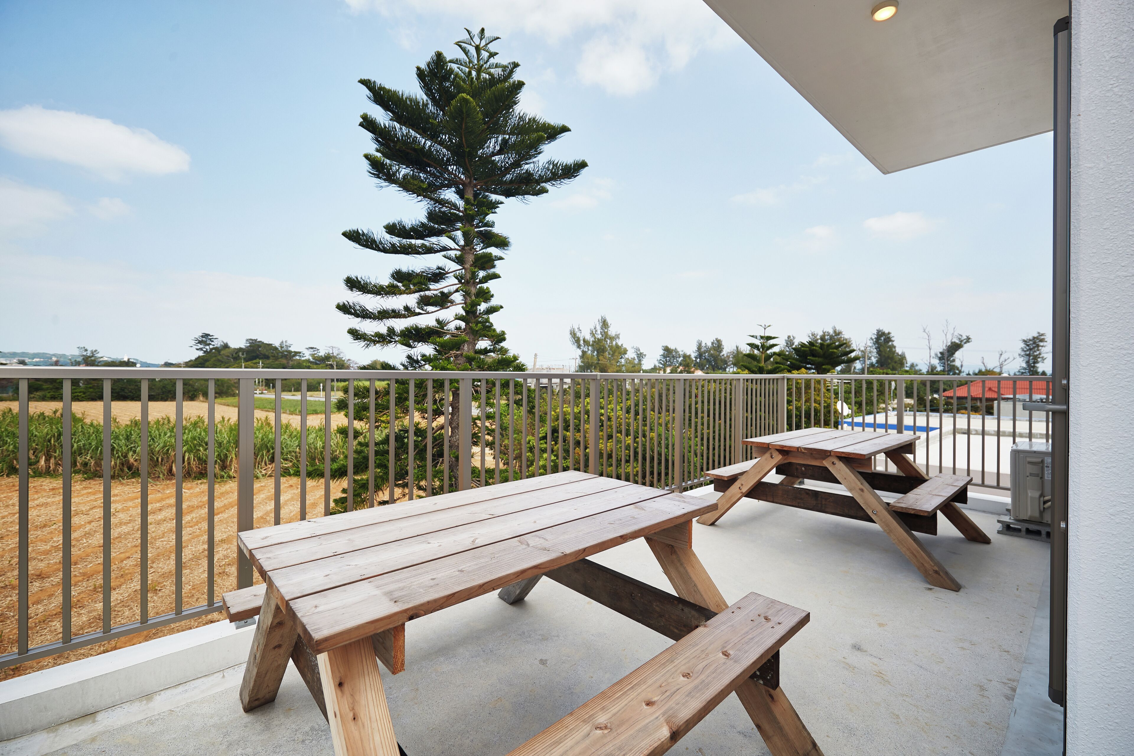 An outdoor patio with wooden picnic tables and a metal railing.