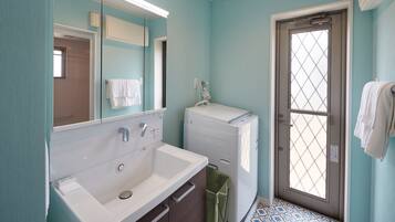 A bathroom with a white sink, a mirror, a window with a grid pattern, and a door.